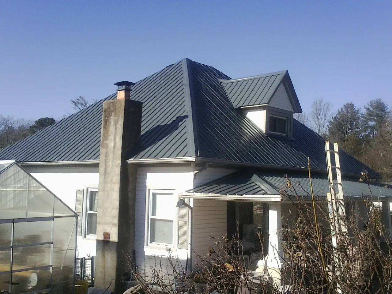 Dark blue standing seam metal roof on a white farmhouse with dormer — Slate & Tile Roof Repair by Roofing Brothers in Pollocksville