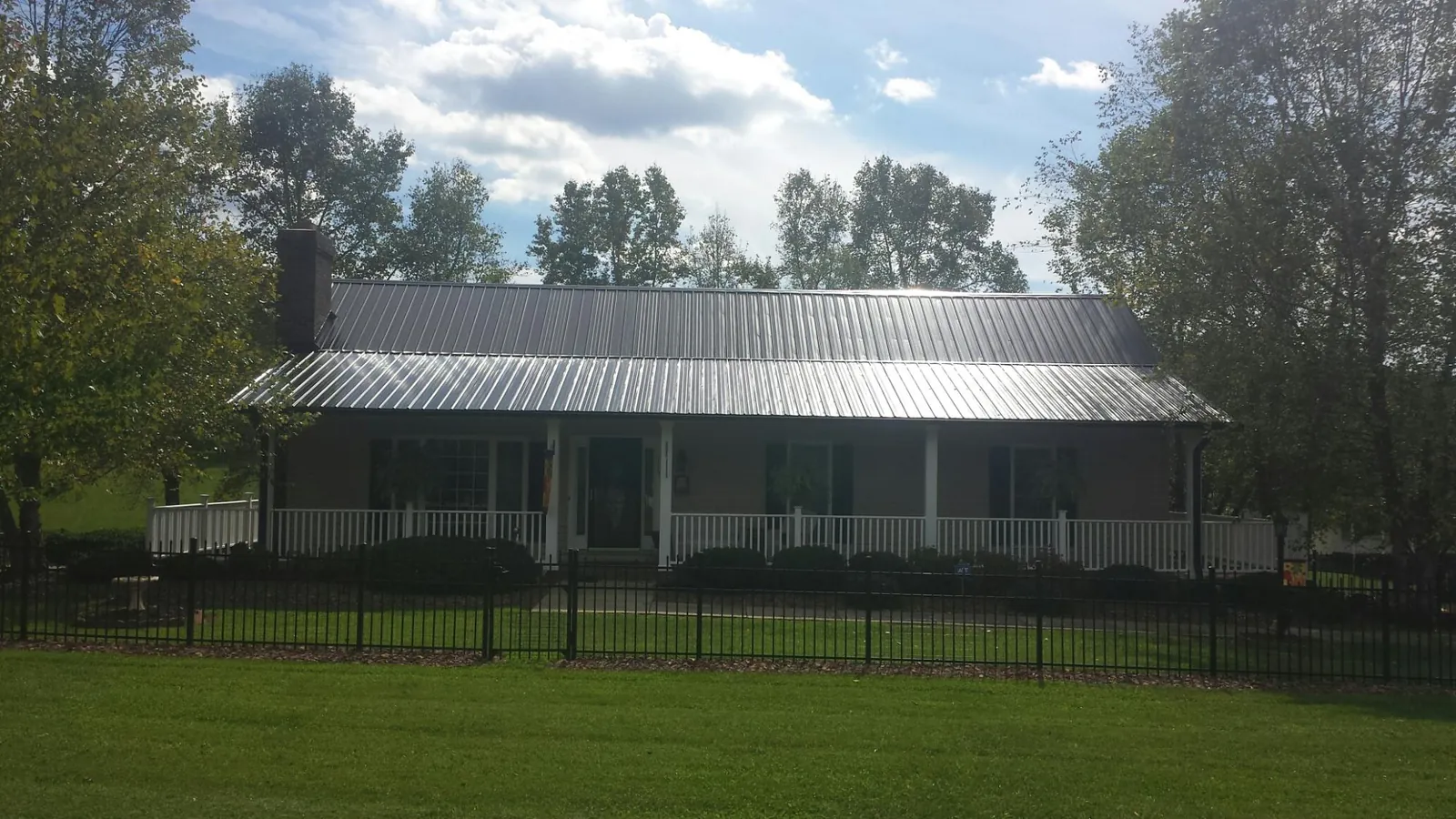 Gray metal roof on a brick ranch with a full width front porch — Gutter Guard Installation work by our crew in Pollocksville